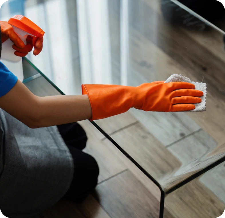 Person wiping glass table with cloth