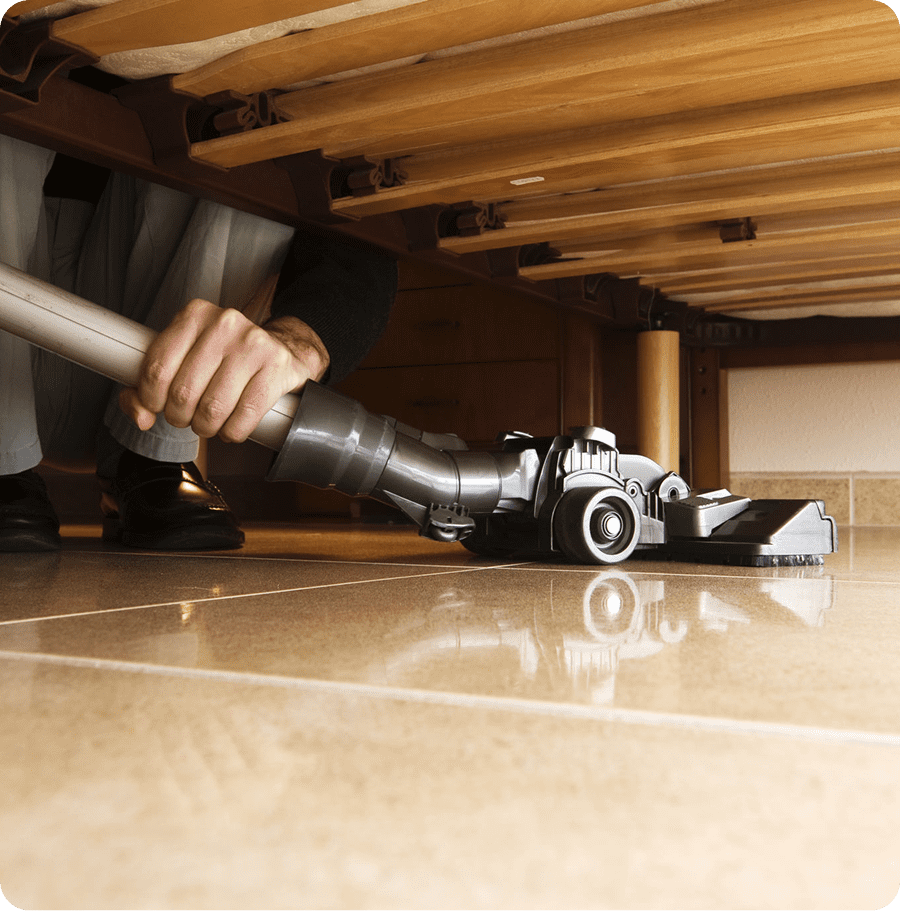 Person vacuuming beneath furniture