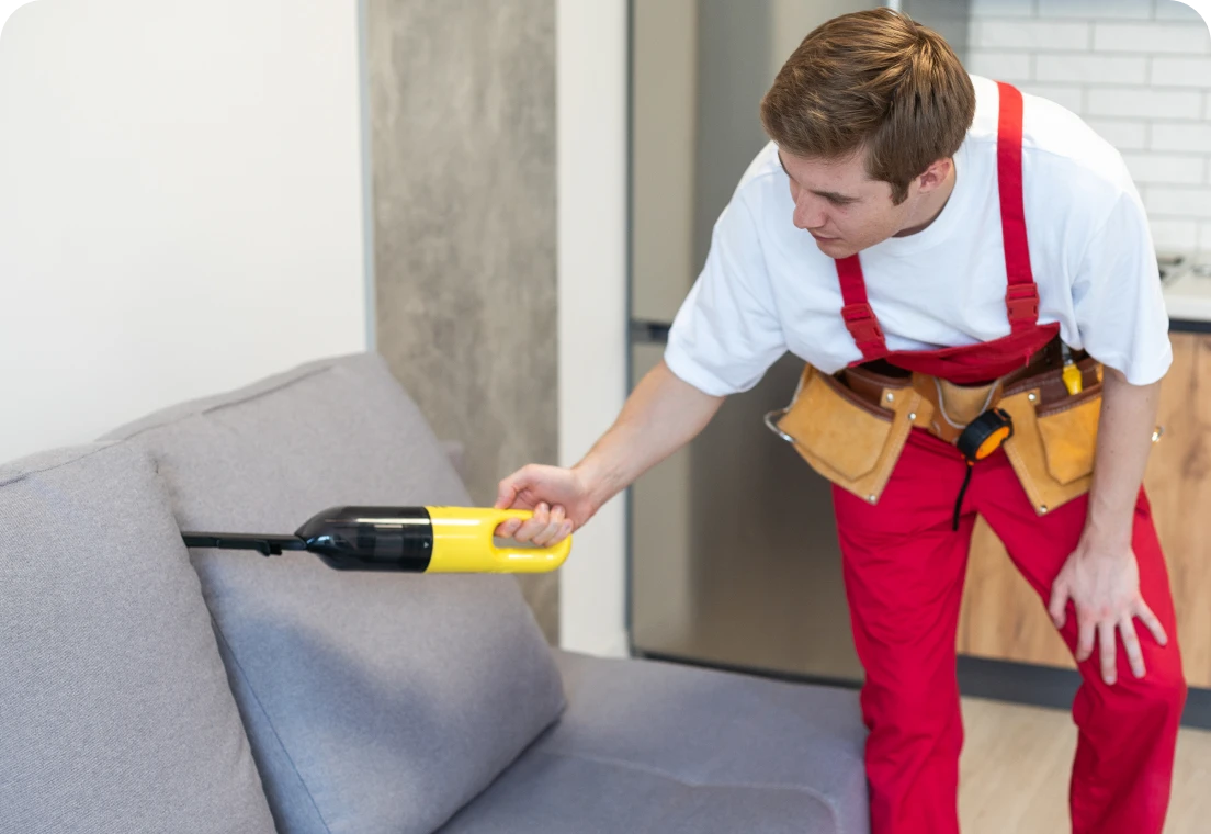 Person vacuuming gray sofa cushions
